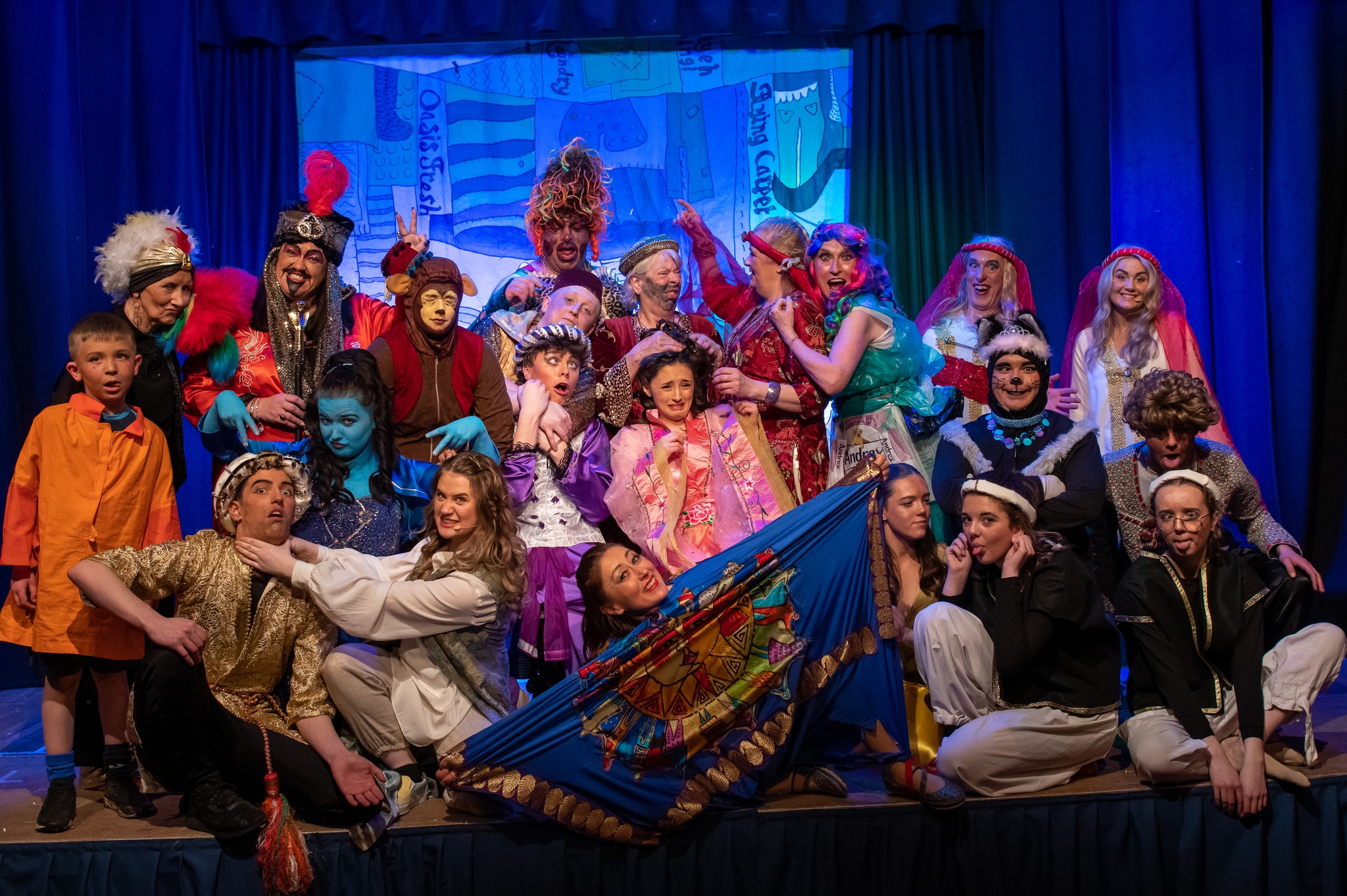 A photo of the cast of Aladdin from 2023, with all the characters on stage pulling silly or strange faces.